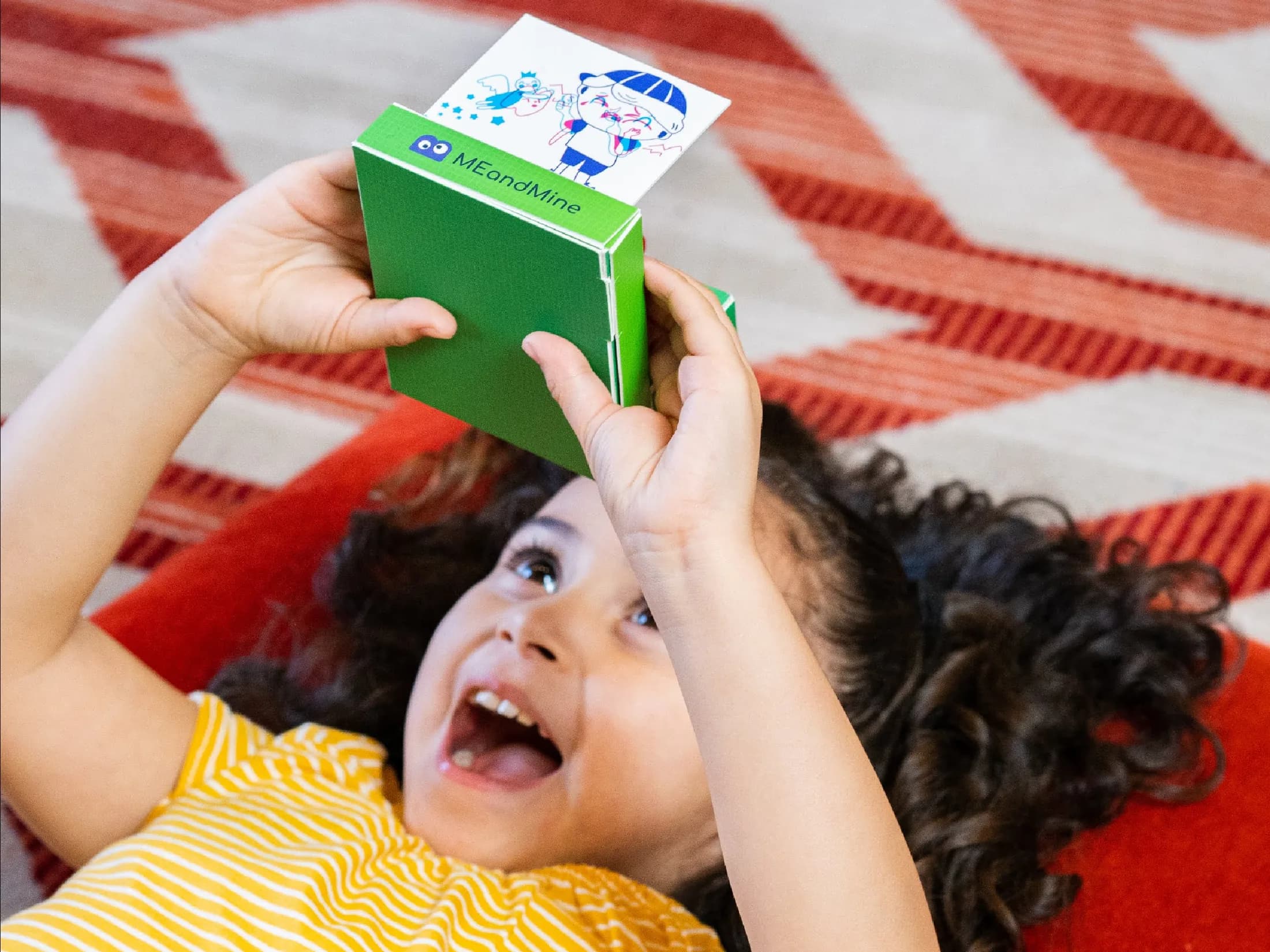 A delighted child holding the green AHA! Brain Memory Camera above her face